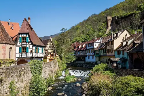 Vue sur le village de Kaysersberg, avec ses maisons à colombages et son château médiéval en arrière-plan.