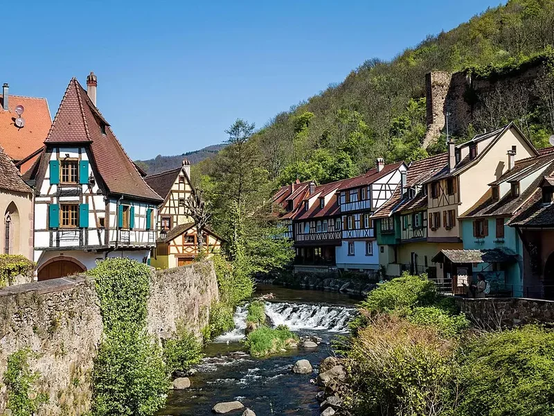 Vue sur le village de Kaysersberg, avec ses maisons à colombages et son château médiéval en arrière-plan.