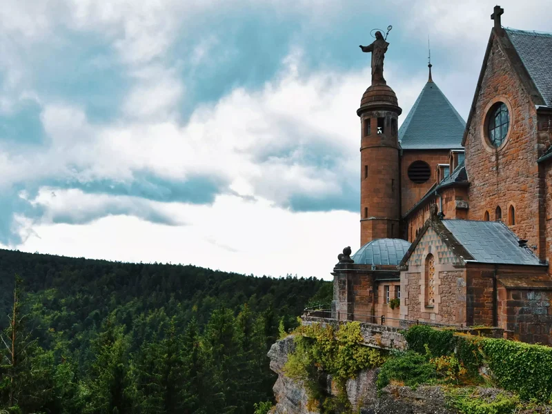 Vue sur le monastère du Mont Saint-Odile, perché sur la colline, entouré de forêt.