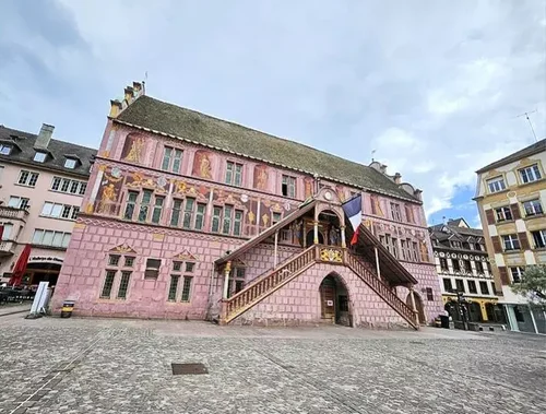 Façade Renaissance rouge et or de l’Hôtel de Ville de Mulhouse, ornée de décors peints et d’un escalier extérieur.