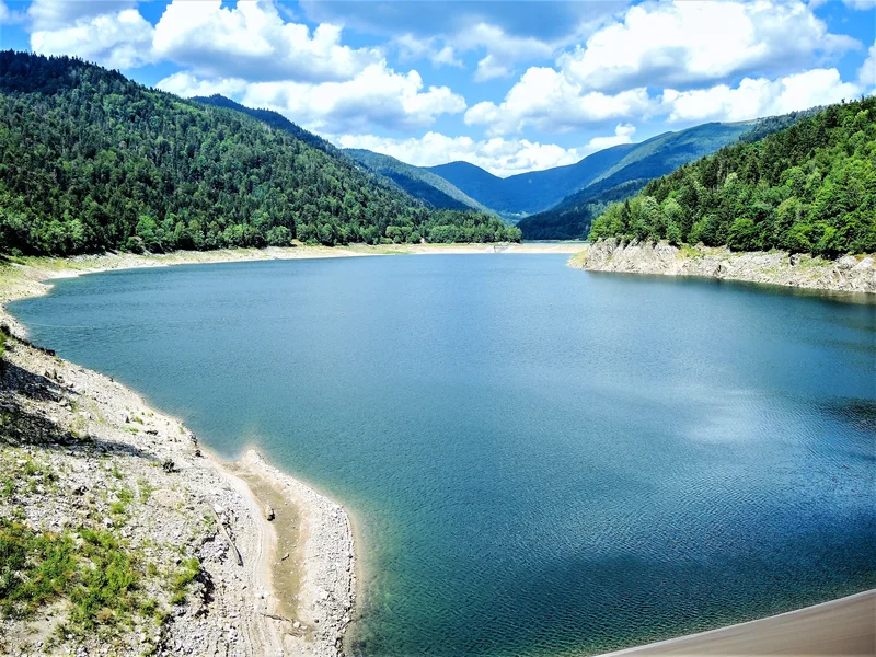 Vue du lac de Kruth-Wildenstein depuis le barrage, avec l’étendue d’eau entourée de montagnes et de forêt.