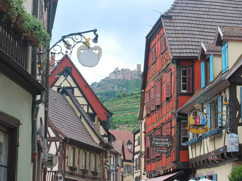 Panorama de la ville avec un château médiéval en arrière-plan, entouré de collines et de forêts.