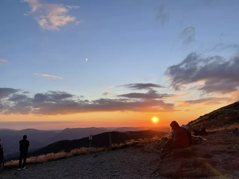 Coucher de soleil au sommet du col, avec les crêtes et vallées des Vosges baignées de lumière dorée.