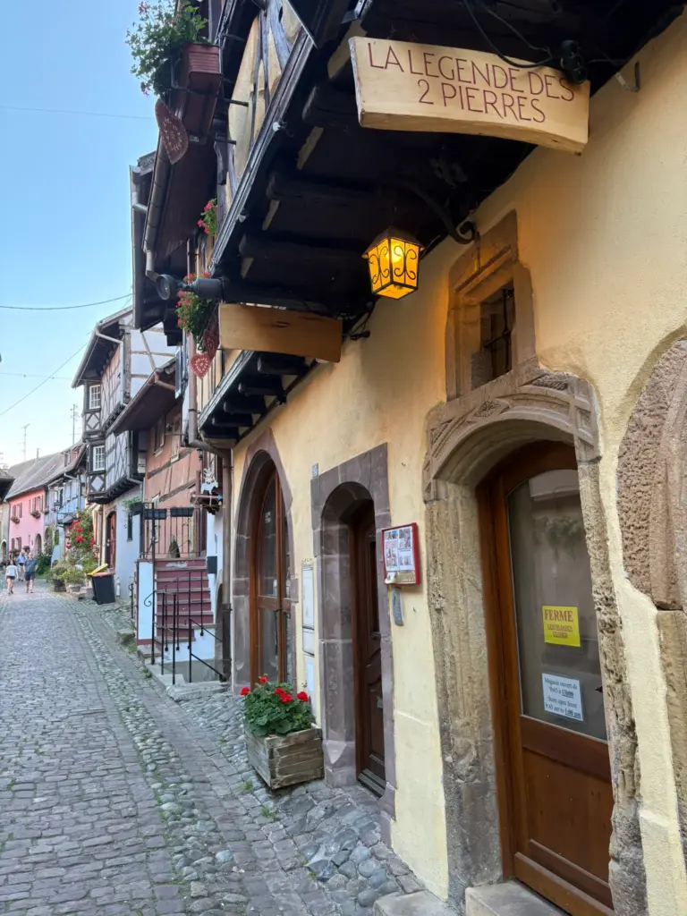 Ruelle pavée du village d’Eguisheim bordée de maisons à colombages fleuries typiques de l’Alsace
